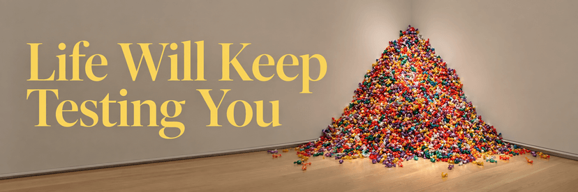 A colorful pyramid of wrapped candies piled in the corner of a minimalist gallery, beside large yellow serif text reading “Life Will Keep Testing You.” That is clear, descriptive, and good for accessibility without overexplaining the image.